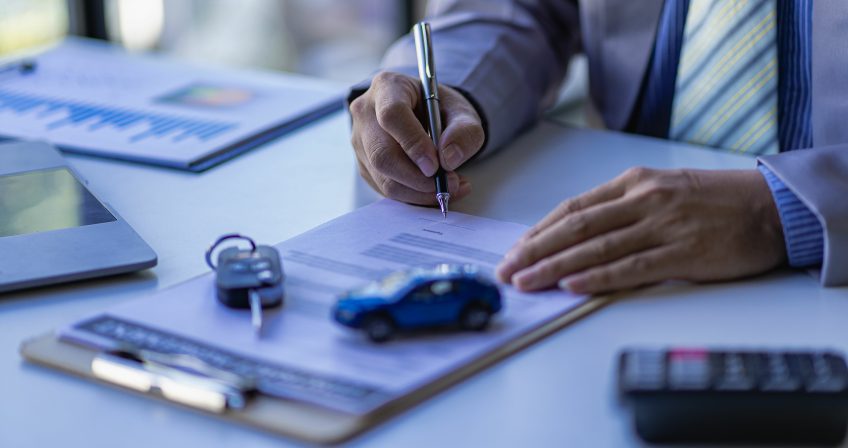 auto insurance agent writing up an auto insurance policy on his desk. Auto insurance essentials policy owners should know.