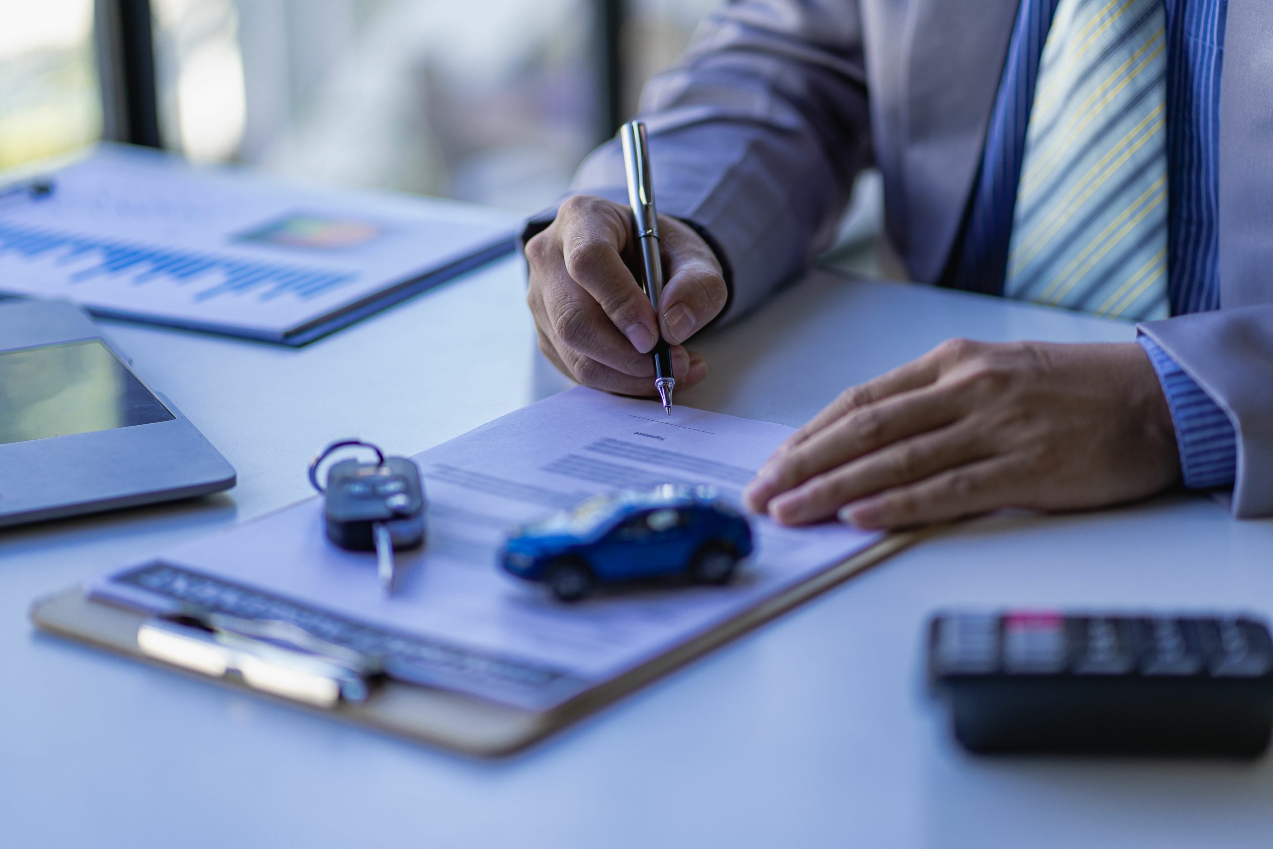 auto insurance agent writing up an auto insurance policy on his desk. Auto insurance essentials policy owners should know.