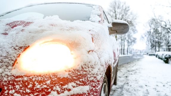 Red car with snow covering it's front hood.