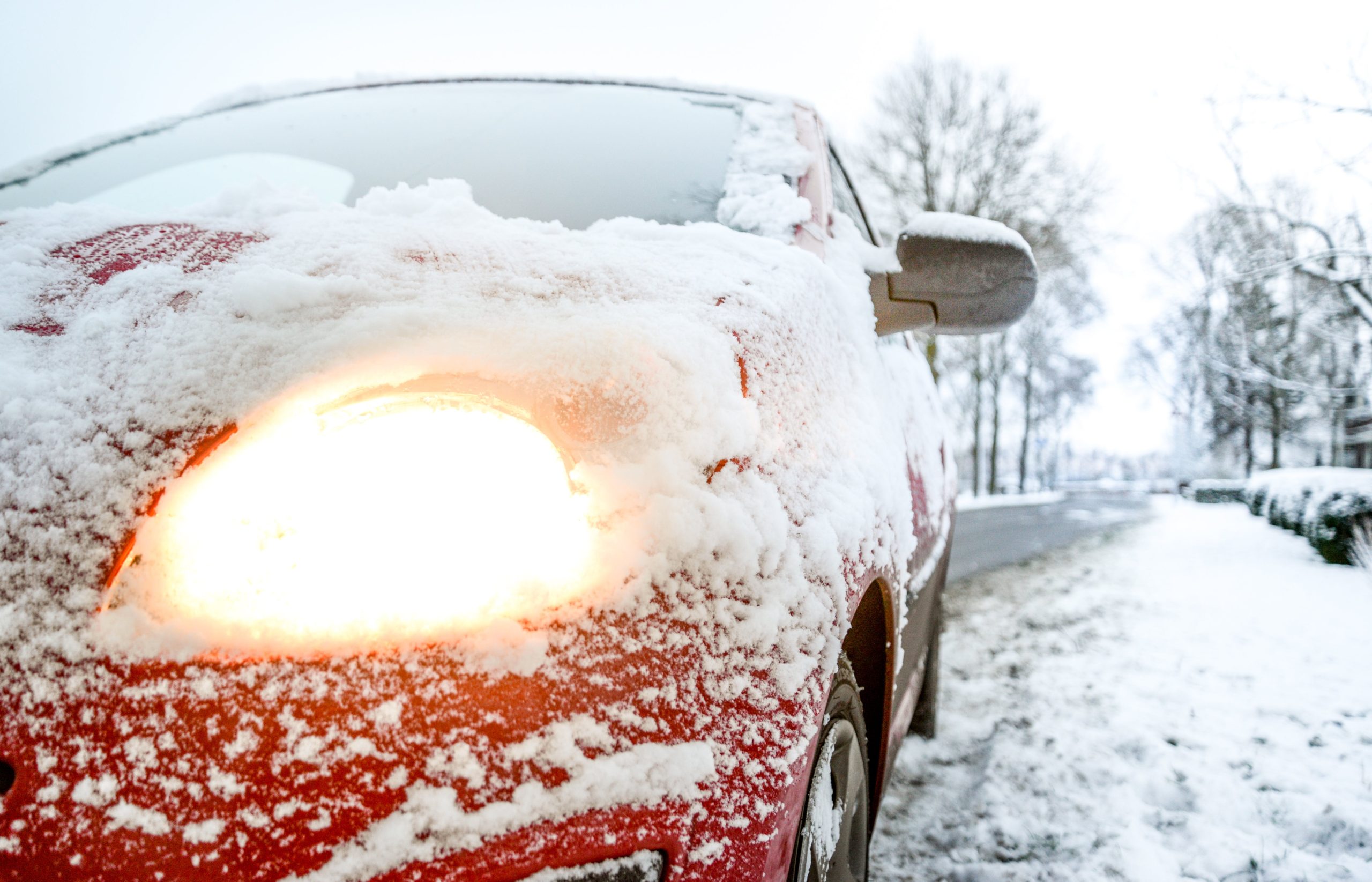 Red car with snow covering it's front hood.