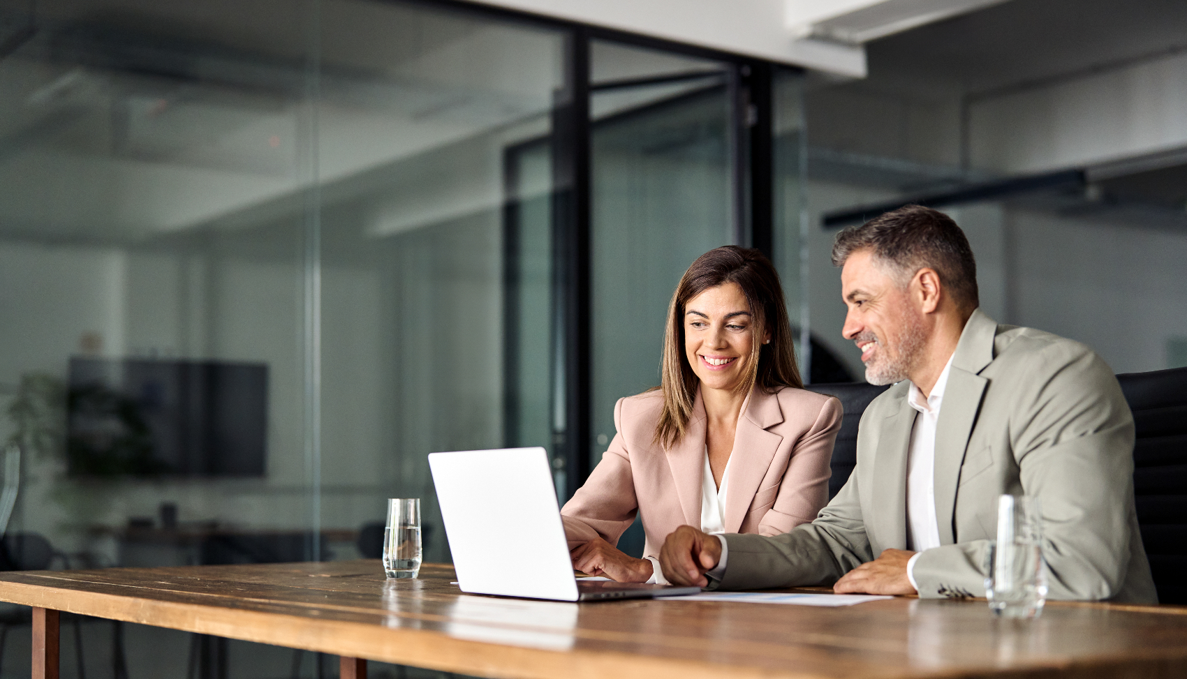 A man and woman sitting at a table and looking at a laptop