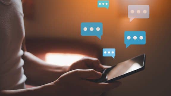 Person using a smartphone with digital chat icons, representing emergency communication apps during network outages