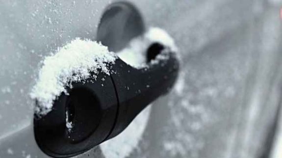 Frozen car door handle covered in snow during icy winter conditions