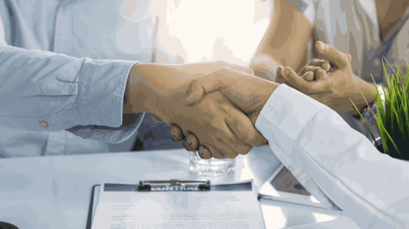 Two business professionals shaking hands over a signed contract, symbolizing a successful business agreement and partnership.