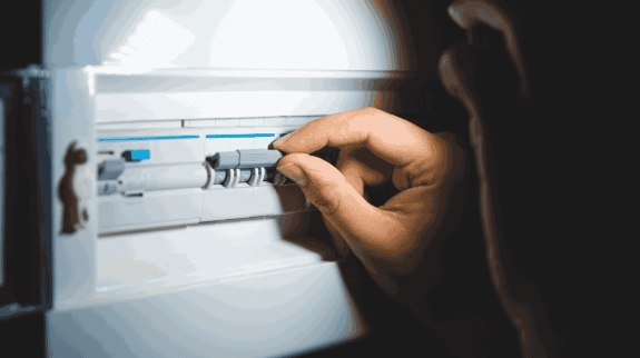 Hand switching on circuit breakers in a home electrical panel for power control and electrical safety.