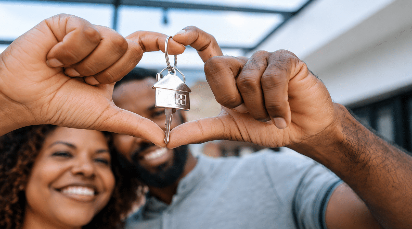New homeowners holding house keys in a heart shape, celebrating the purchase of their first home